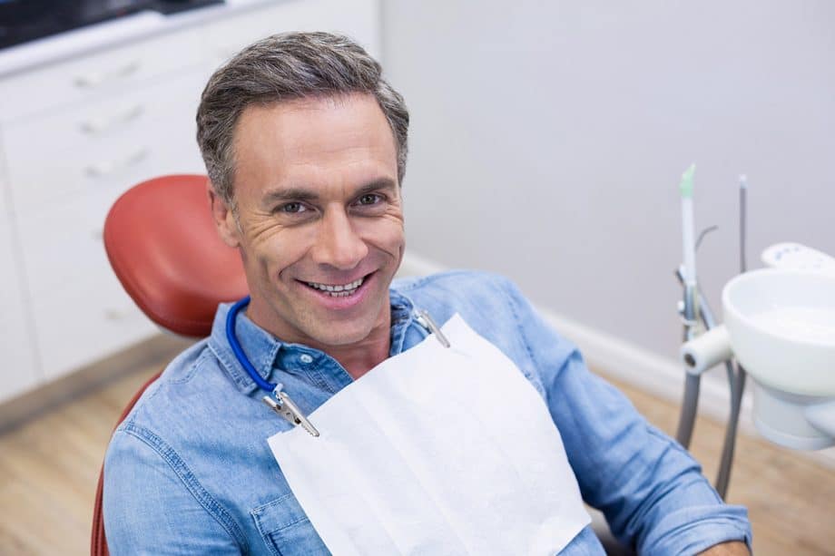 man smiles up from dental chair