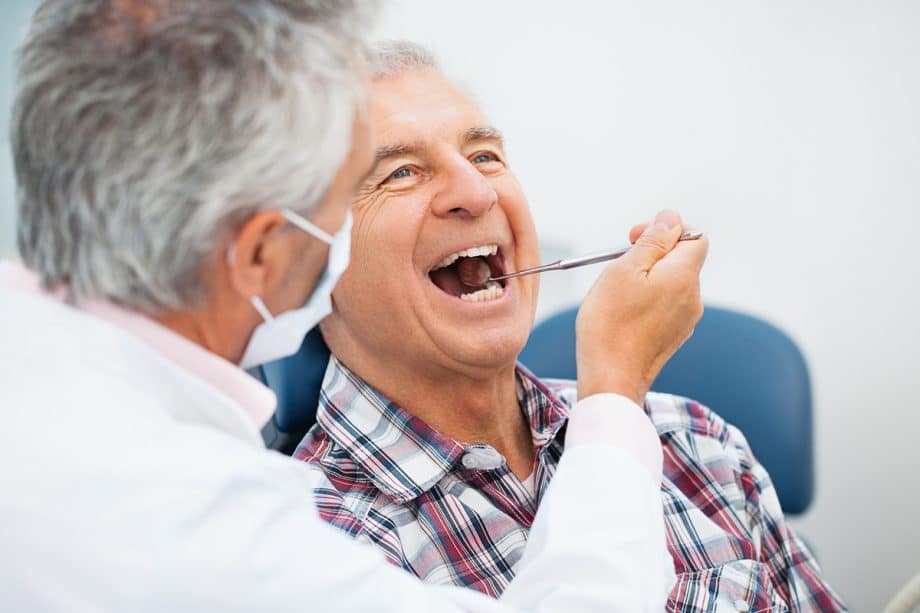 a dentist checks a mature man's teeth